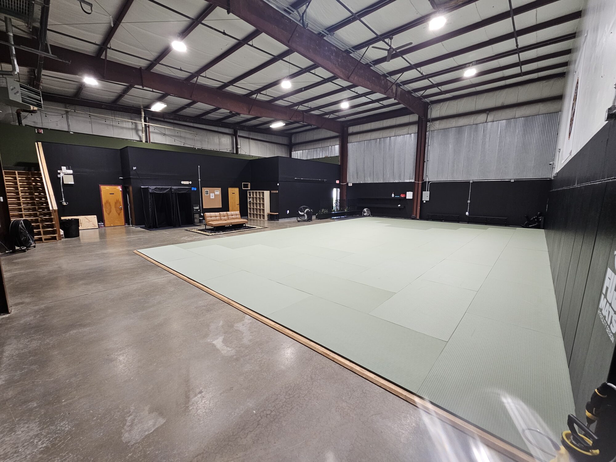 Arete academy floor — mats, belt display, and lounge